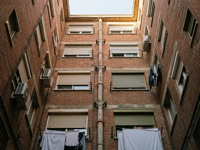 Patio interior de un bloque de ladrillo de los años setenta con una bajante gris